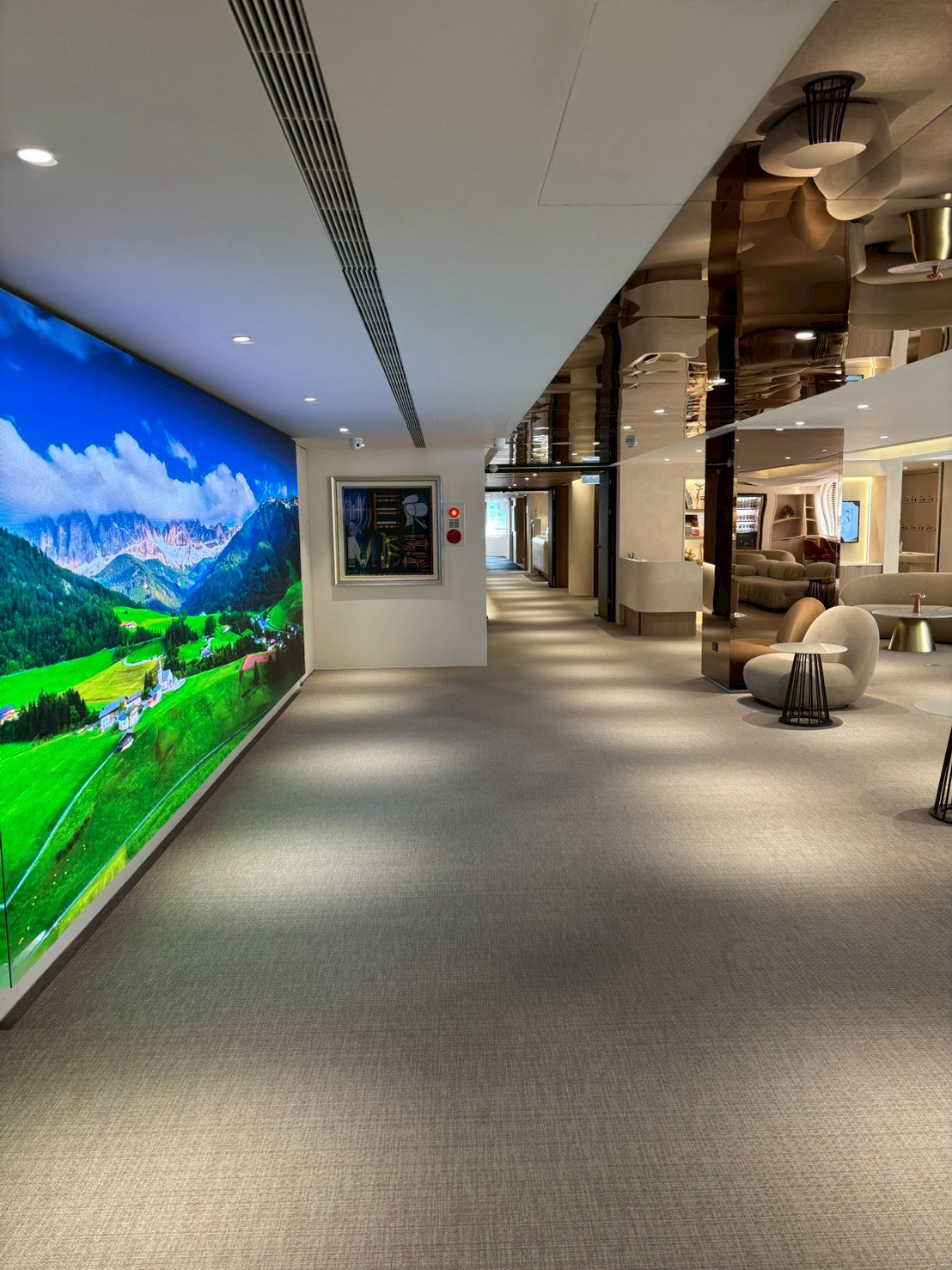 美力時尚診所 忠孝旗艦店寬敞的走廊一側，巨大的 LED 牆顯示著連綿的山脈風景